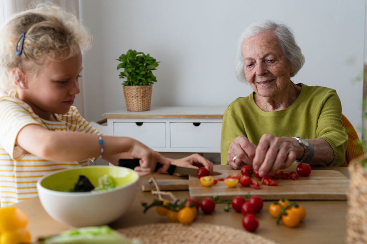 

Seniorin und Enkelin bereiten einen Salat zu.