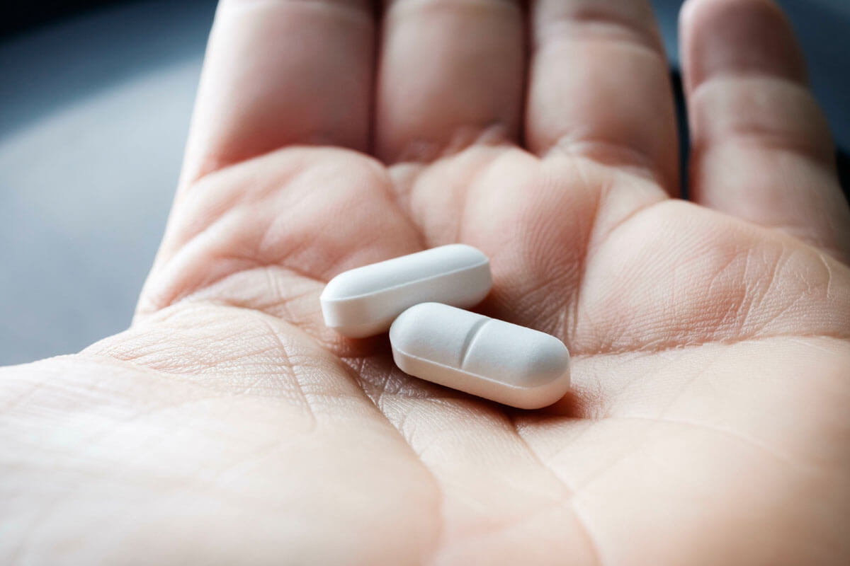 

Großaufnahme einer Handinnenfläche mit 2 Tabletten.